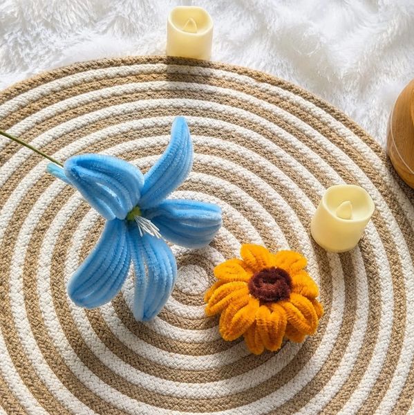 Blue and orange fabric flowers on a circular woven mat with candles.