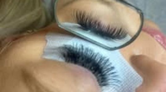 Close-up of eyelash extensions being applied with a mirror reflection.
