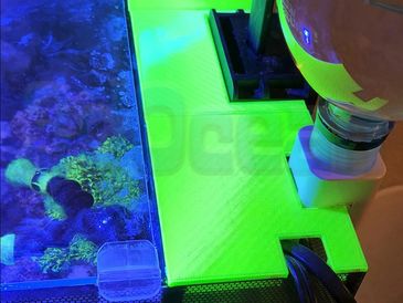A neon green 3D-printed aquarium cover with a water bottle setup.