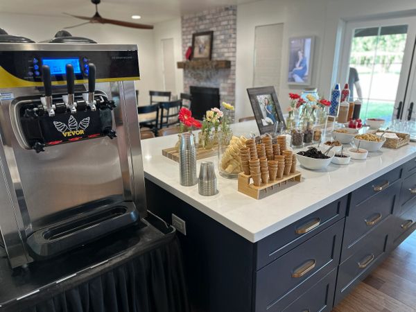 A modern kitchen island with soft serve ice cream machine and toppings setup.