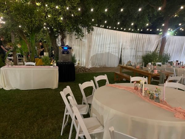 Outdoor event setup with string lights and decorated tables.