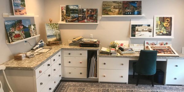 Art studio corner with paintings, a desk, and storage drawers.