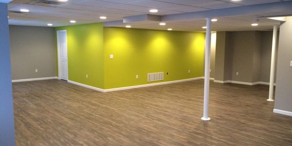 Spacious basement with wood flooring, grey and lime green walls, and recessed lighting.