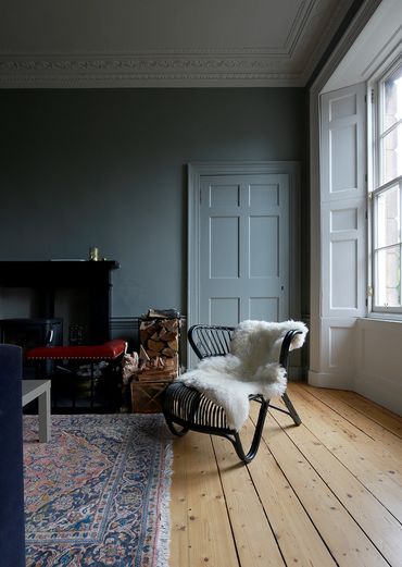 Bamboo armchair with sheepskin in front of fireplace of grade II listed Georgian house 