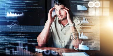 Stressed man analyzing complex data on multiple transparent screens.