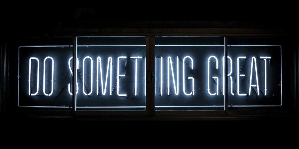 A picture of a neon sign that says "do something great"