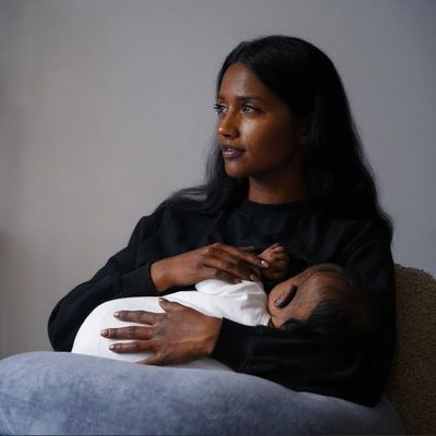 A mother tenderly holds her sleeping baby, gazing thoughtfully into the distance.