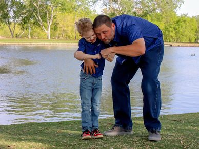Man playing with boy by the lake.