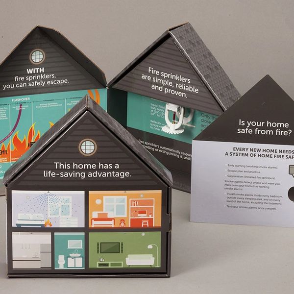 Educational fire safety display shaped like houses, promoting fire sprinklers and home safety tips.