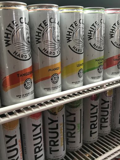 Cans of White Claw and Truly hard seltzers in a fridge.