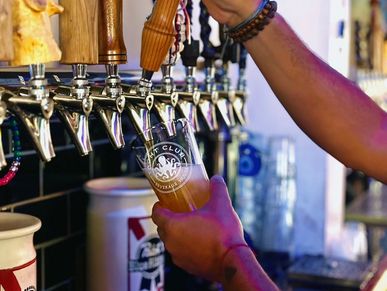 Person pouring beer from a tap into a glass at a bar.