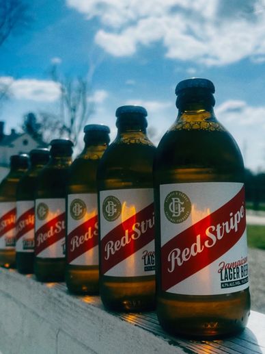 Line of Red Stripe Jamaican lager beer bottles outdoors.