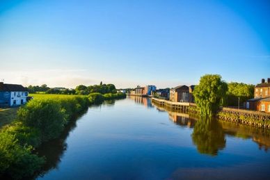 Calm river flowing through a town with clear blue sky.