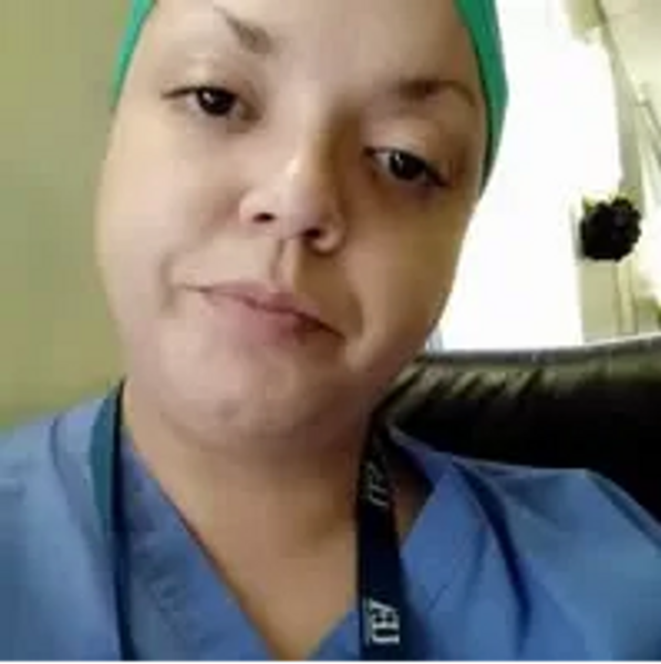 A healthcare worker in scrubs and a green cap.