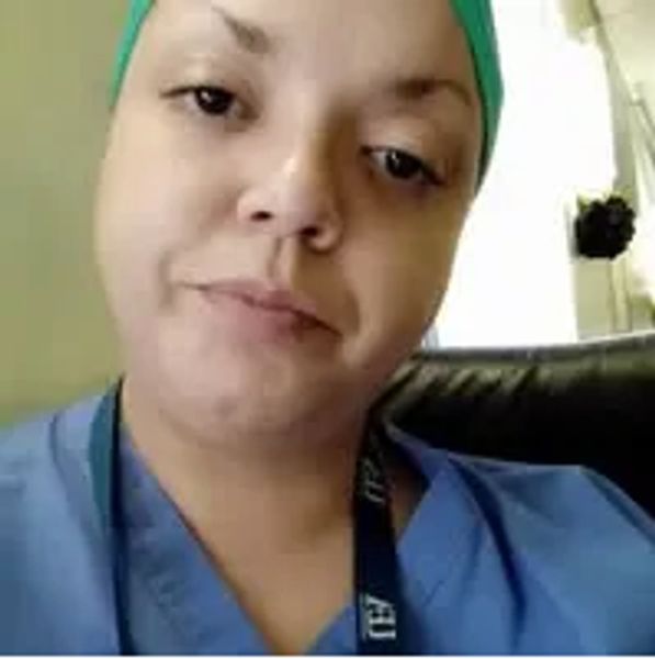 A healthcare worker in scrubs and a green cap.