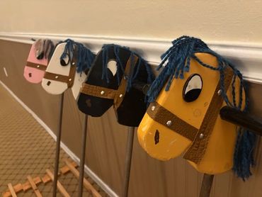 A row of colorful hobby horse heads lined up indoors.