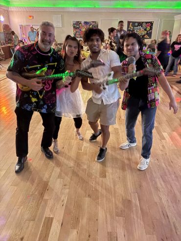 Group of friends playing toy guitars indoors.