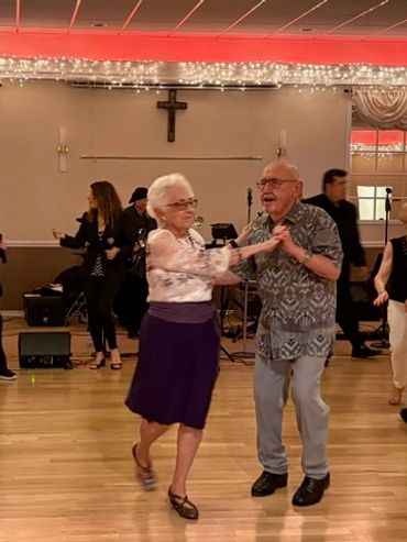 Elderly couple dancing joyfully indoors.