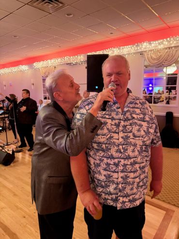 Two men singing together at a party.