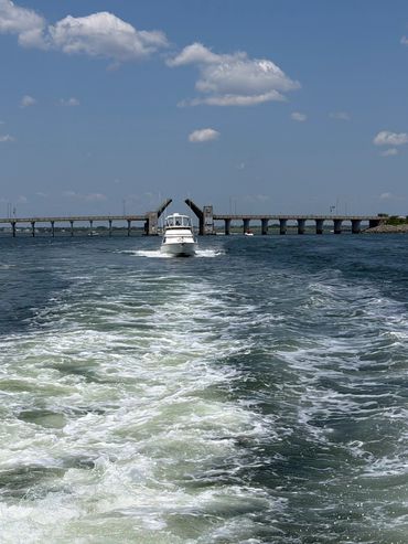 Boat passing through a raised drawbridge on a sunny day.