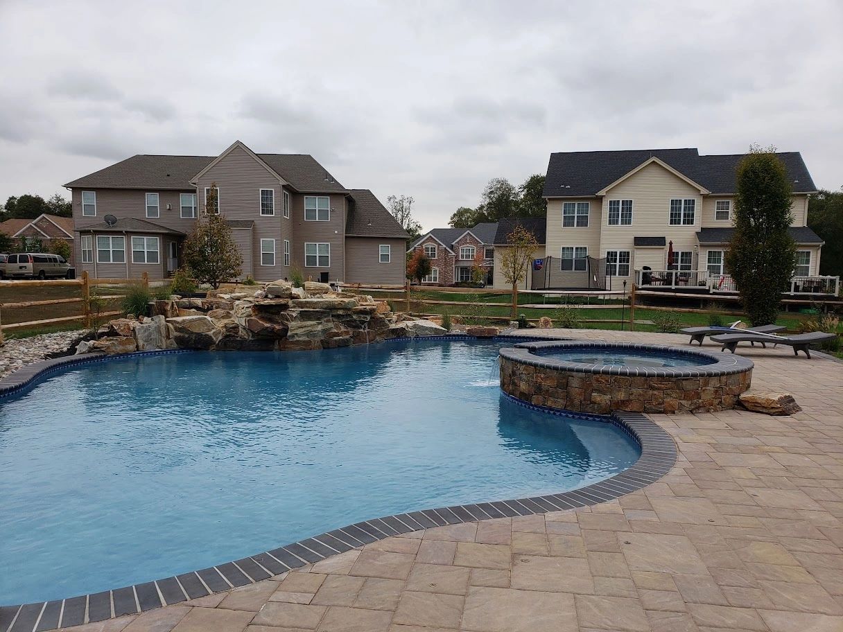 Boulder and flagstone waterfall into pool. Veneer stone, swimming pool, hot tub, patio, landscape.