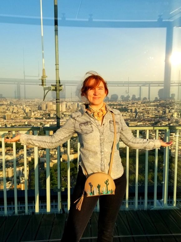 A photo of Samantha Smith with her arms out to either side standing on a high rise over Paris.