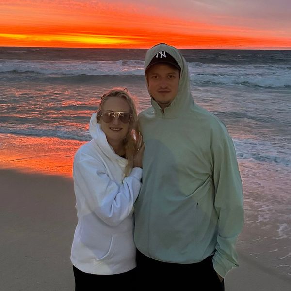 Jo and her son posing on the beach during a vibrant sunset.