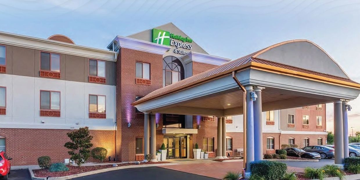 Holiday Inn Express hotel exterior with entrance canopy and parked cars.
