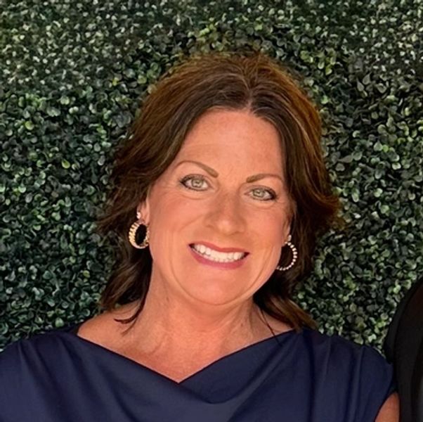 Smiling woman with hoop earrings and dark top.