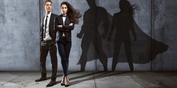 Two professionals casting superhero shadows on a wall behind them.