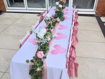 Outdoor table with pink and white floral decorations.