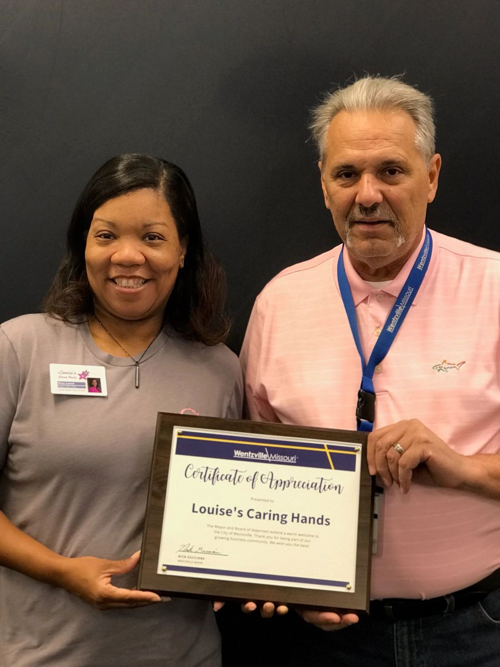 Two people holding a certificate of appreciation.