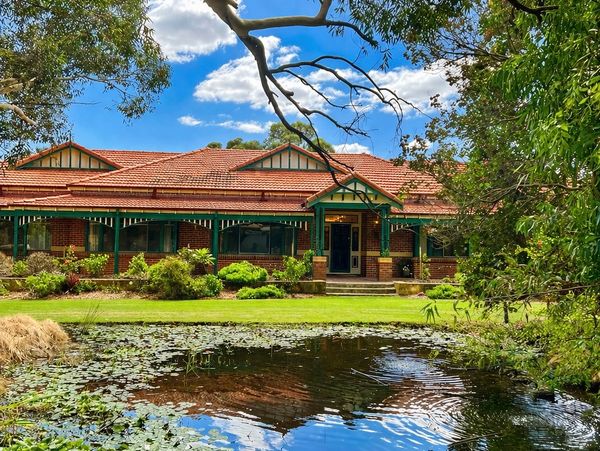 A charming house with a pond in front under a bright blue sky.