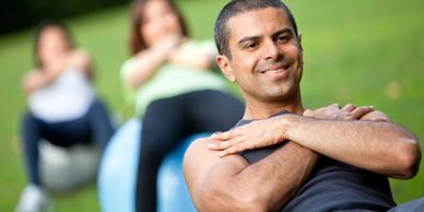 WorkoutStyles Group of two women and one man working out at the park using a body ball