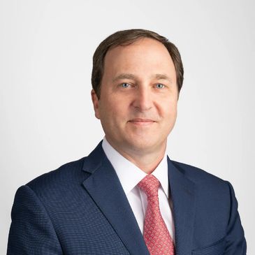 Professional man in navy suit and red tie smiling.
