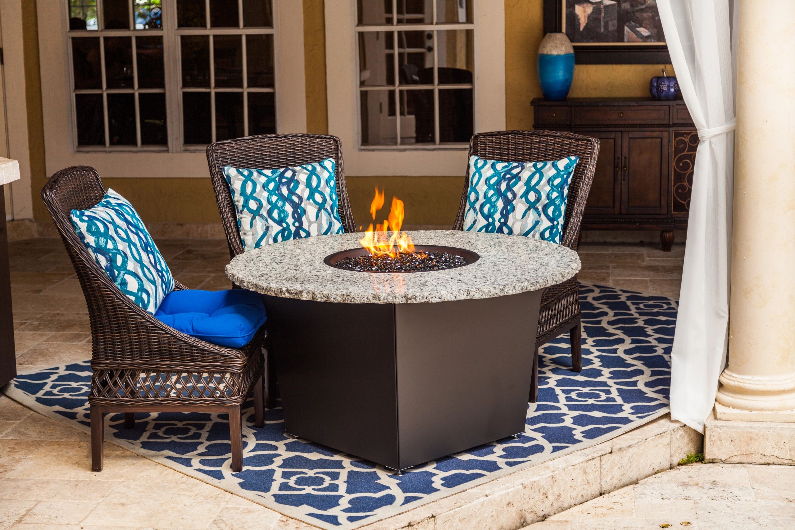 Round gas fire pit table with fire in an outdoor setting