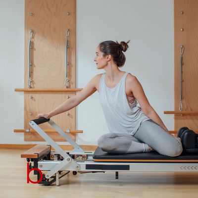 Woman practicing Pilates on a reformer machine in a studio.