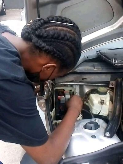 girl with braids working on a car