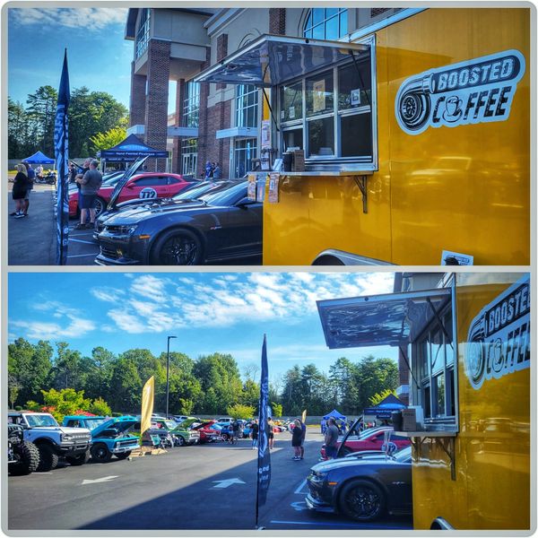 A yellow Boosted Coffee truck at a car show with classic and modern cars lined up.