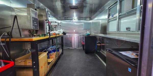 Interior of a clean and organized food truck with stainless steel appliances.