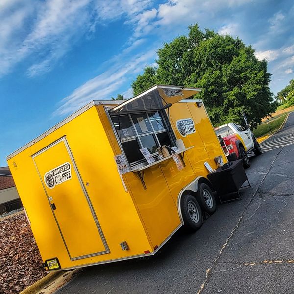 Bright yellow Boosted Coffee food truck parked outside on a sunny day.