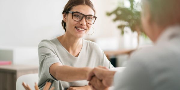 Smiling woman shaking hands in a professional setting.