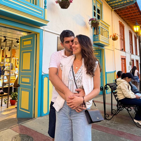 Pareja abrazándose frente a una tienda colorida.
