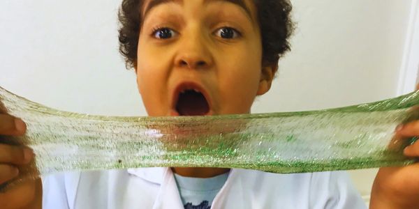 Child excitedly stretching green glitter slime.