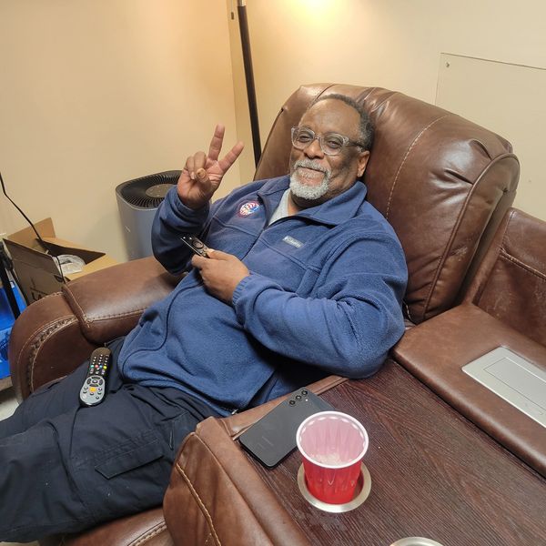 Man sitting on a leather chair making a peace sign.