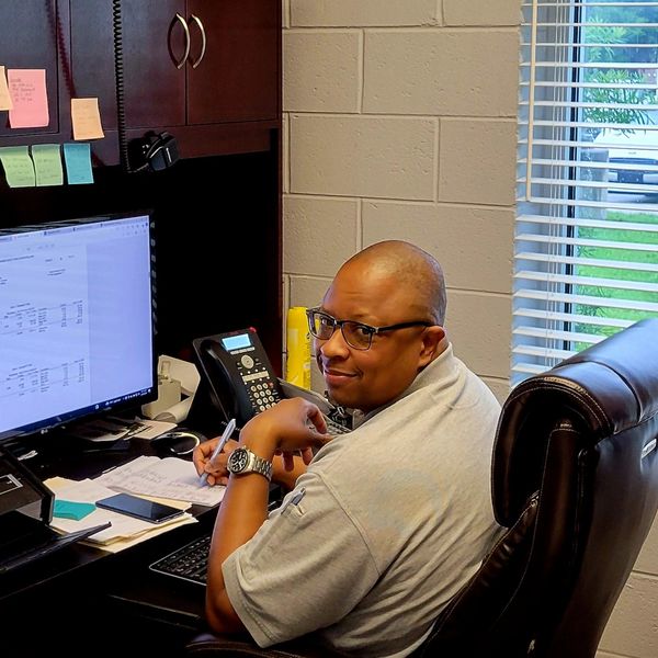 Man working at desk with computer, phone, and notes.