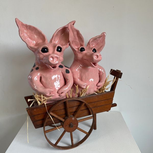 Two pink pigs riding in a hay wagon