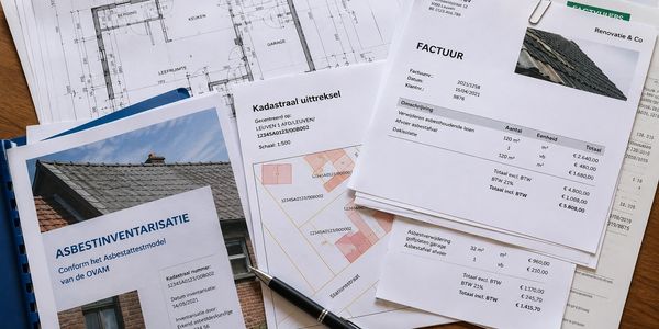 Documenten over asbestinventarisatie, kadaster en factuur liegen op tafel.