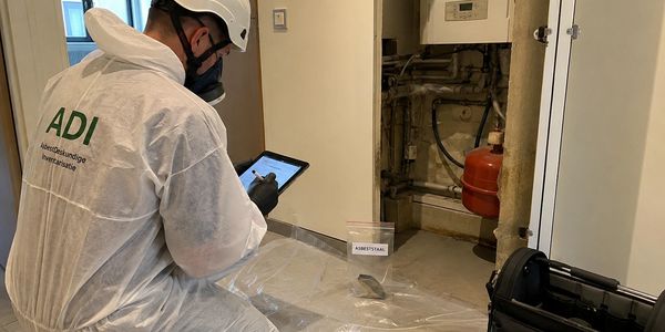 Persoon in beschermend pak inspecteert stalen monster binnenshuis.