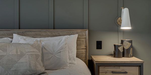 Grey paneled headboard wall with white pendant light.